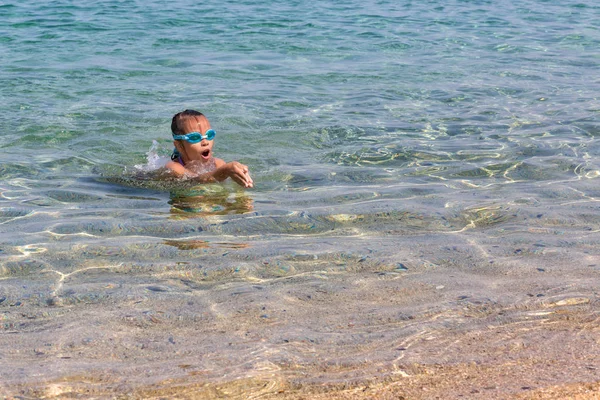 Joven turista en gafas deportivas de natación flota en el mar Egeo en la costa de la península de Sithonia —  Fotos de Stock