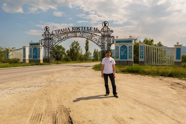 Tourist man near the gate at the entrance to village of Koktebel — Stock Photo, Image