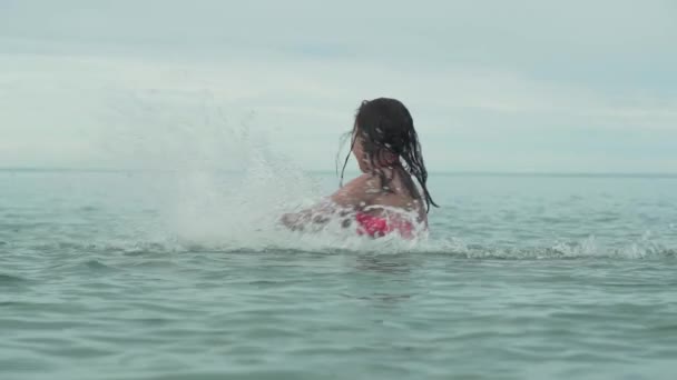 Alegre feliz joven jugando con salpicaduras de agua en el mar cámara lenta material de archivo de vídeo — Vídeos de Stock