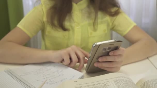 Девочка-подросток делает домашнюю работу со смартфоном — стоковое видео