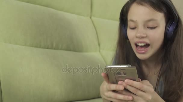 Beautiful teen girl in headphones singing karaoke songs in smartphone stock footage video — Stock Video