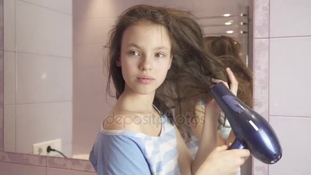 Красива дівчина-підліток сушить волосся фен у ванній кімнаті відео — стокове відео