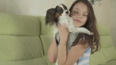 Güzel mutlu genç kız eğleniyor köpeğiyle Papillon Continental oyuncak İspanyol stok görüntüleri video oynarken