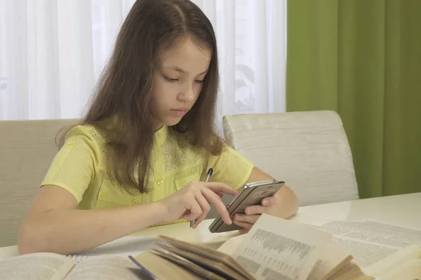 Девочка-подросток делает домашнее задание со смартфоном — стоковое фото