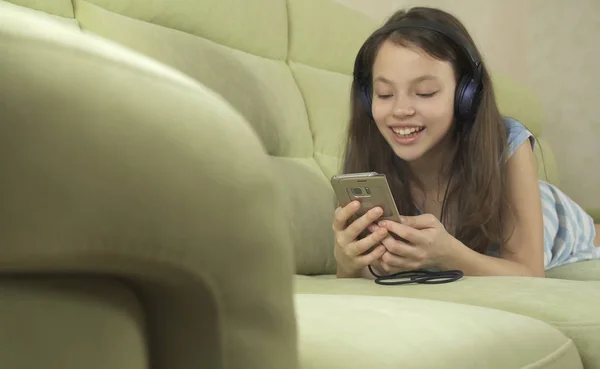 Beautiful teen girl in headphones singing karaoke songs in smartphone — Stock Photo, Image