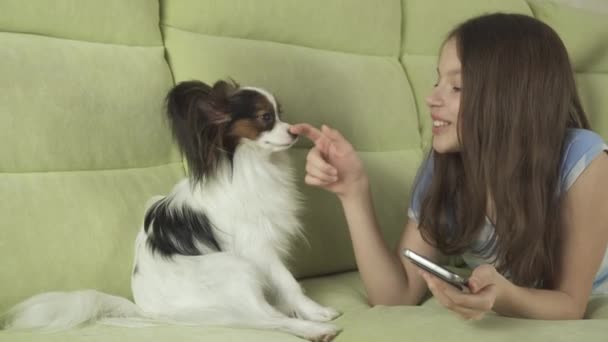 Mooie gelukkig tienermeisje communiceren in smartphone en met haar hond stock footage video — Stockvideo