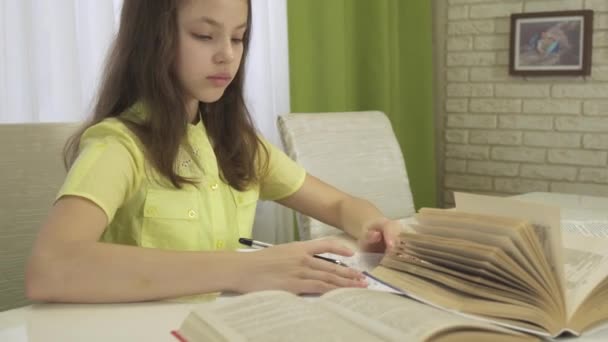 Adolescente menina faz lição de casa na mesa de estoque de imagens de vídeo — Vídeo de Stock