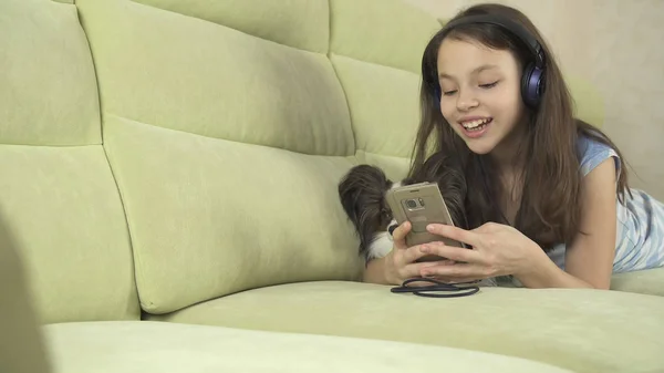 美丽的少女在耳机唱歌在智能手机与狗的卡拉 ok 歌曲 — 图库照片
