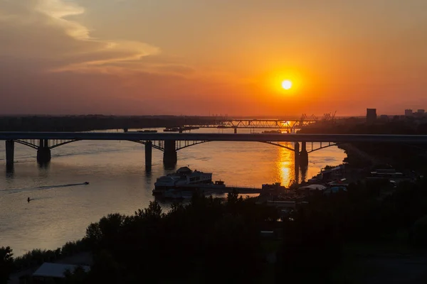 Ηλιοβασίλεμα πάνω από τη γέφυρα Octyabrsky στην απέναντι όχθη ποταμού Ob σε Νοβοσιμπίρσκ — Φωτογραφία Αρχείου