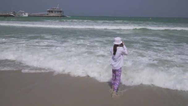 Tienermeisje neemt foto's van de golven van de zee van de Perzische Golf op smartphone op het strand van Dubai stock footage video — Stockvideo