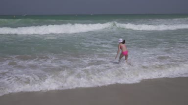 Genç kız bir mayo içinde mutlu Basra Körfezi dalgalar halinde Dubai beach stok görüntüleri video atlar.