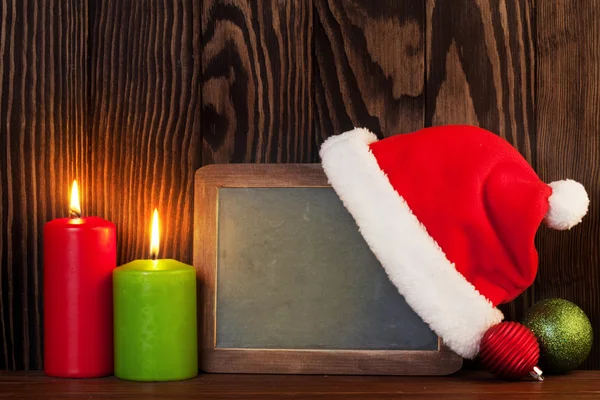 Christmas chalkboard, candles and santa hat — Stock fotografie