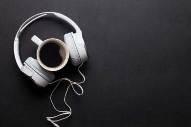 Kulaklık ve siyah masada kahve fincanı