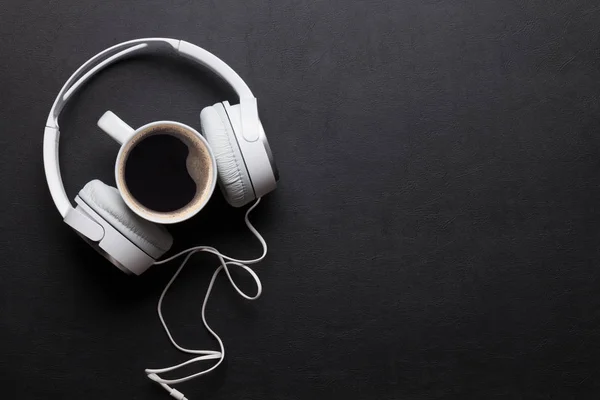 Kulaklık ve siyah masada kahve fincanı — Stok fotoğraf