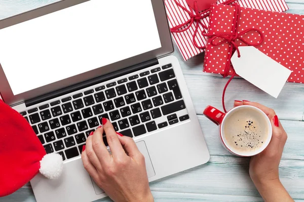 Frau arbeitet am Laptop und verpackt Geschenke — Stockfoto