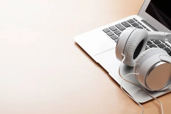 Headphones and laptop on wooden table — Stock Photo, Image