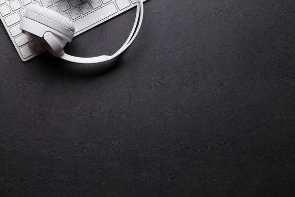 Наушники и клавиатура на черном столе
