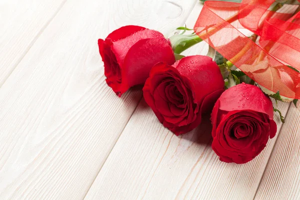 Rosas vermelhas sobre mesa de madeira — Fotografia de Stock