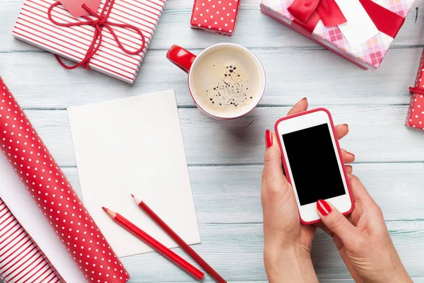 Frau hält Smartphone in der Hand und verpackt Geschenke — Stockfoto