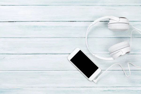 Смартфон і навушники на столі — стокове фото