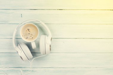 Headphones and coffee cup on wooden table clipart
