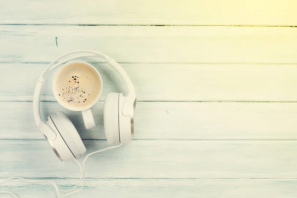 Headphones e xícara de café na mesa de madeira — Fotografia de Stock