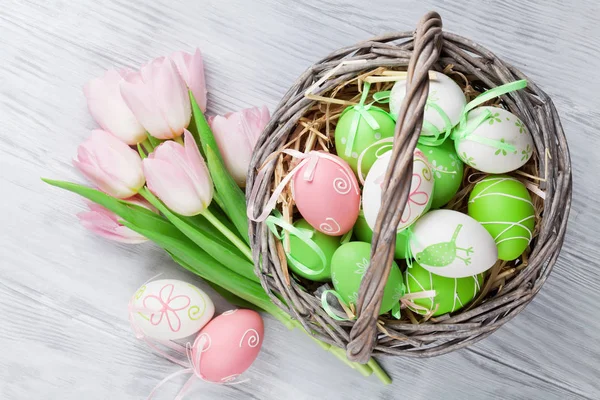 Ovos de Páscoa em cesta e tulipas — Fotografia de Stock