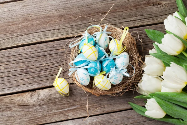Ovos de Páscoa em ninho e tulipas brancas — Fotografia de Stock