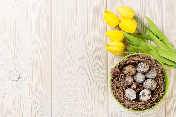 Eieren in nest en gele tulpen — Stockfoto
