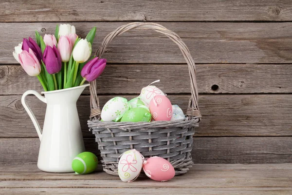 Huevos de Pascua en cesta y tulipanes — Foto de Stock