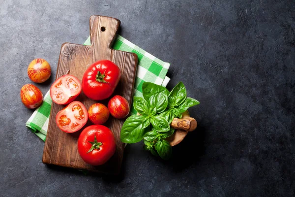 Tomatoes and basil on stone table — Stock Photo, Image