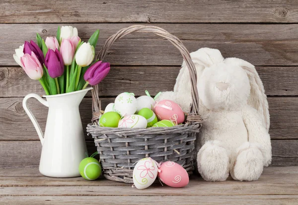 Brinquedo de coelho, ovos de páscoa e tulipas — Fotografia de Stock