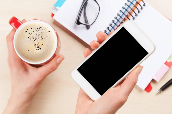 Female hands holding smartphone and coffee cup — Stock Photo, Image