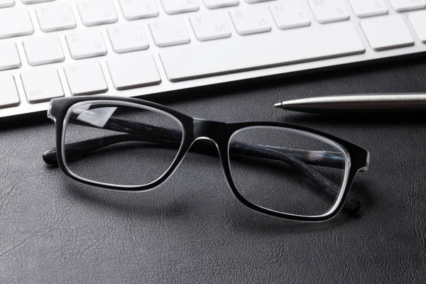 eyeglasses, keyboard and pen