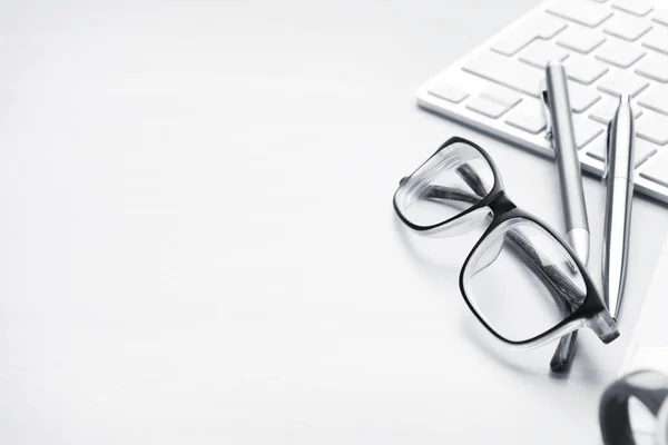 Computer keyboard, eyeglasses and pens — Stock Photo, Image