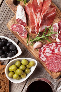 Salam, dilimlenmiş jambon, sosis, jambon, pastırma, tost, zeytin. Et meze tabağı ve ahşap masa üzerinde kırmızı şarap. Üstten Görünüm