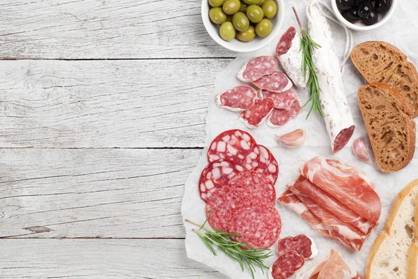 Salam, dilimlenmiş jambon, sosis, jambon, pastırma, tost, zeytin. Ahşap masa üzerinde et meze tabağı. Üstten Görünüm alanı ile