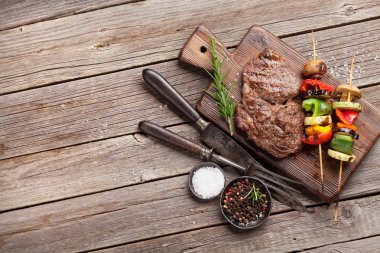 Izgara sebze ve sığır eti biftek ahşap masa üzerinde kesme tahtası üzerinde. Kopya alanı ile Üstten Görünüm