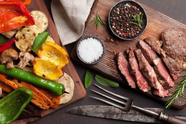 Izgara sebze ve sığır eti biftek ahşap masa üzerinde kesme tahtası üzerinde. Üstten Görünüm