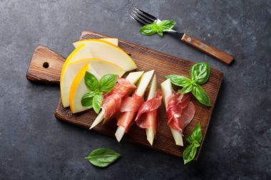 Jambon ve fesleğen ile taze kavun. Antipasti. Karanlık taş masada Üstten Görünüm