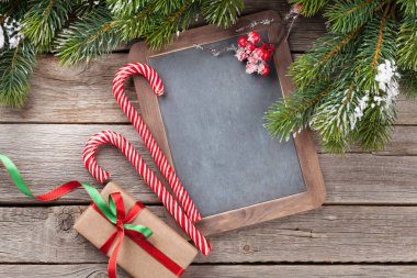 Noel hediye kutusu, şekerler ve karlı köknar ağacı ahşap masa üzerinde. Boş yazı tahtası ile Üstten Görünüm 