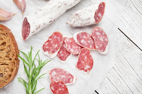 Salami and bread. Meat antipasto on wooden table. Top view