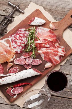 Salam, dilimlenmiş jambon, sosis, jambon, pastırma, tost, zeytin. Et meze tabağı ve ahşap masa üzerinde kırmızı şarap. Üstten Görünüm