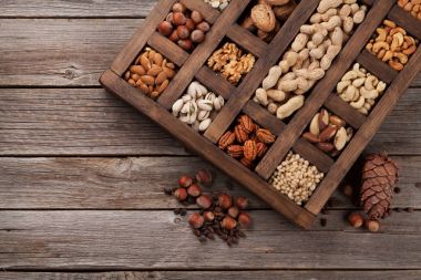 Various nuts selection: peanuts, hazelnuts, chestnuts, walnuts, pistachios and pecans in wooden box. Top view clipart