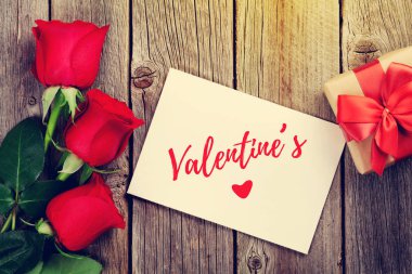 Kırmızı gül, tebrik kartı ve hediye kutusu ahşap arka plan üzerinde. Kopya alanı ile Üstten Görünüm