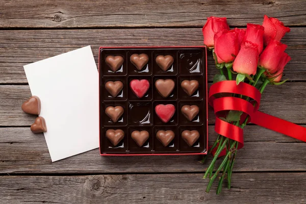 情人节贺卡与红玫瑰和心巧克力盒在木桌上 带空格的顶部视图 — 图库照片