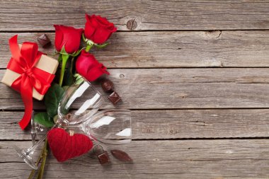 Sevgililer günü tebrik kartı. Kırmızı gül, kalp, şarap gözlük, çikolata ve hediye kutusu ahşap masa üzerinde. Kopya alanı ile Üstten Görünüm