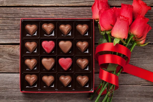 情人节贺卡与红玫瑰和心形巧克力在木背景 顶部视图 — 图库照片