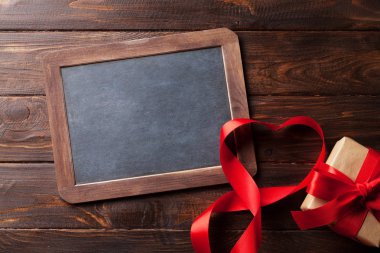 Sevgililer günü tebrik kartı kırmızı kalpli ahşap masa üzerinde şerit ve Hediyelik kutu şeklinde. Kara tahta ile 
