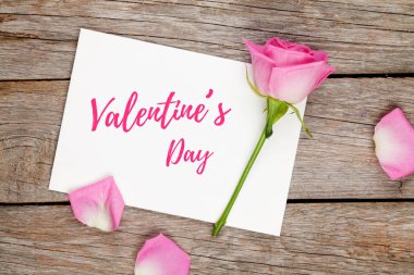 Sevgililer günü tebrik kartı ve pembe ahşap masa üzerinde yükseldi. Kopya alanı ile Üstten Görünüm